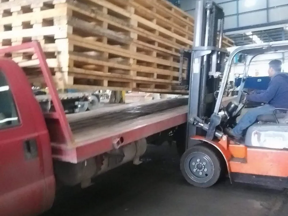 Montacargas cargando tarimas de madera en camión para entrega